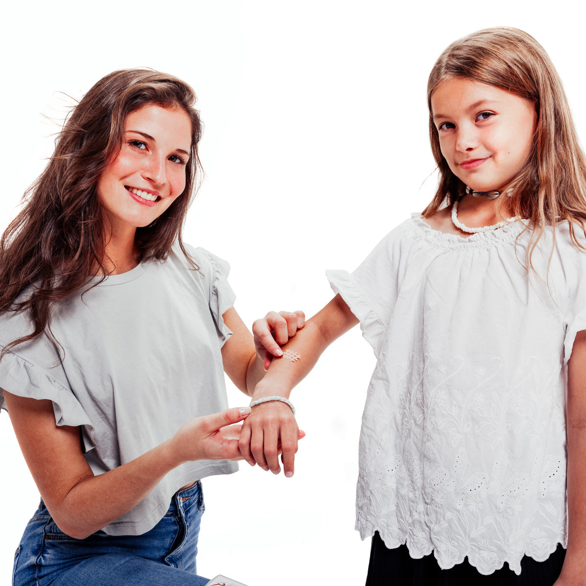 Eine junge Mutter, die ihrer Tochter das Moskinto Pflaster auf den Stich am rechten Arm kleb. Beide schauen freundlich in die Kamera.