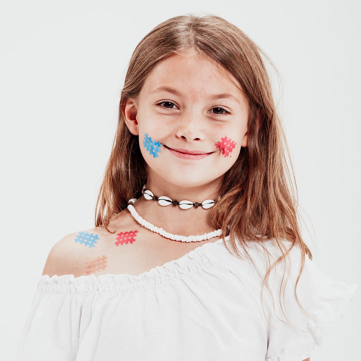 Das Portrait eines jungen Mädchens mit Moskinto Pflastern in Beige, Blau und Pink im Gesicht.