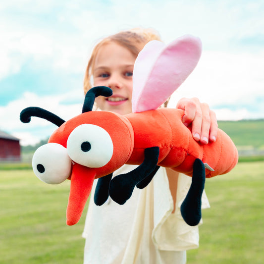 Mädchen hält lachend die Plüschmücke in die Kamera.